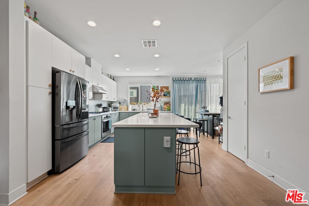 4326 Eagle Rock Boulevard Los Angeles, CA 90041 - Photo 11 of 33 a kitchen with a refrigerator a kitchen island a stove a table and chairs with wooden floor