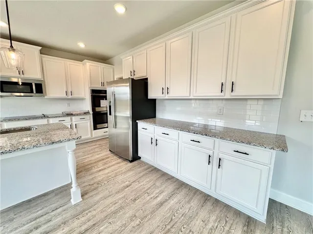 a kitchen with granite countertop white cabinets and stainless steel appliances