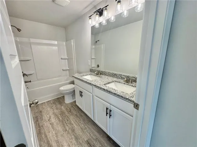 a bathroom with a granite countertop sink a toilet a mirror and shower