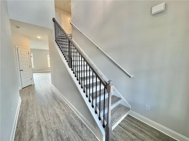 a view of staircase with wooden floor and white walls