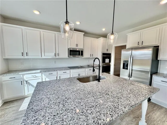 a kitchen with stainless steel appliances granite countertop a sink a stove and a refrigerator