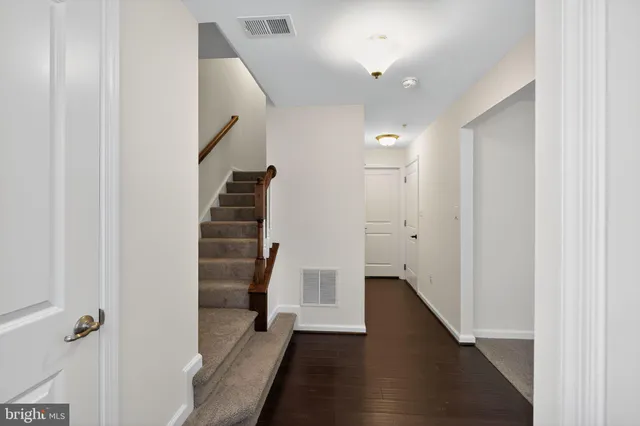 a view of a hallway with stairs and wooden floor