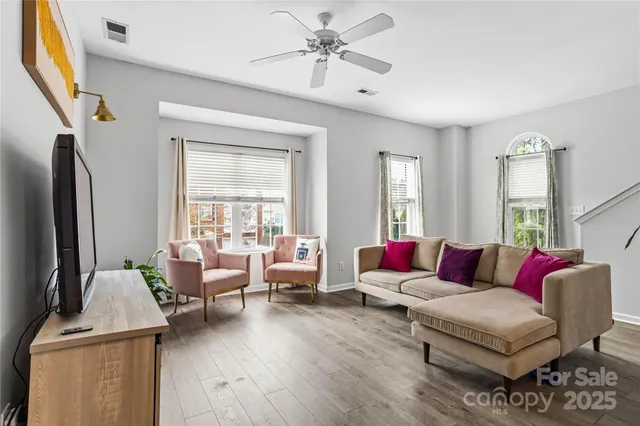 an empty room with windows a fireplace a ceiling fan and wooden floor