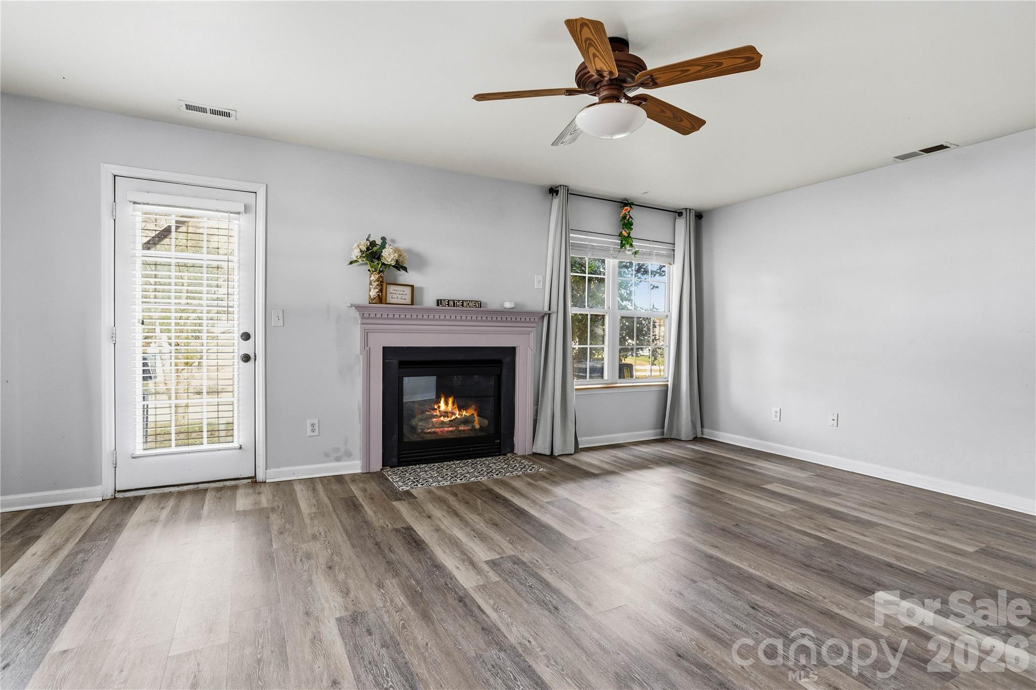 101 Rock Ridge Lane Mount Holly, NC 28120 - Photo 6 of 35 an empty room with windows a fireplace a ceiling fan and wooden floor