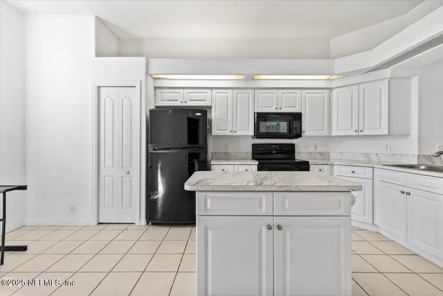 a kitchen with a refrigerator a stove top oven and white cabinets