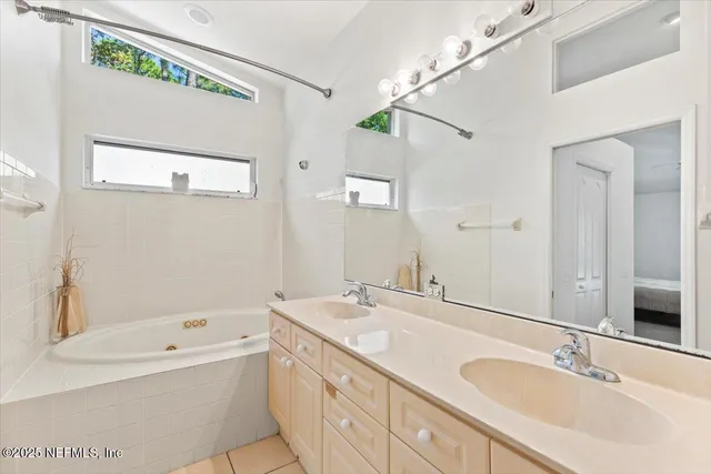 a bathroom with a tub a sink and mirror