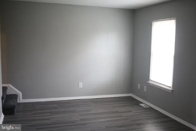a view of an empty room and wooden floor and a window