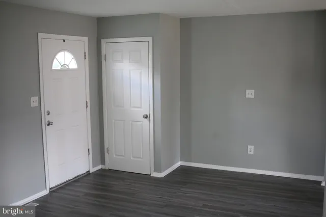a view of an empty room with wooden floor and closet