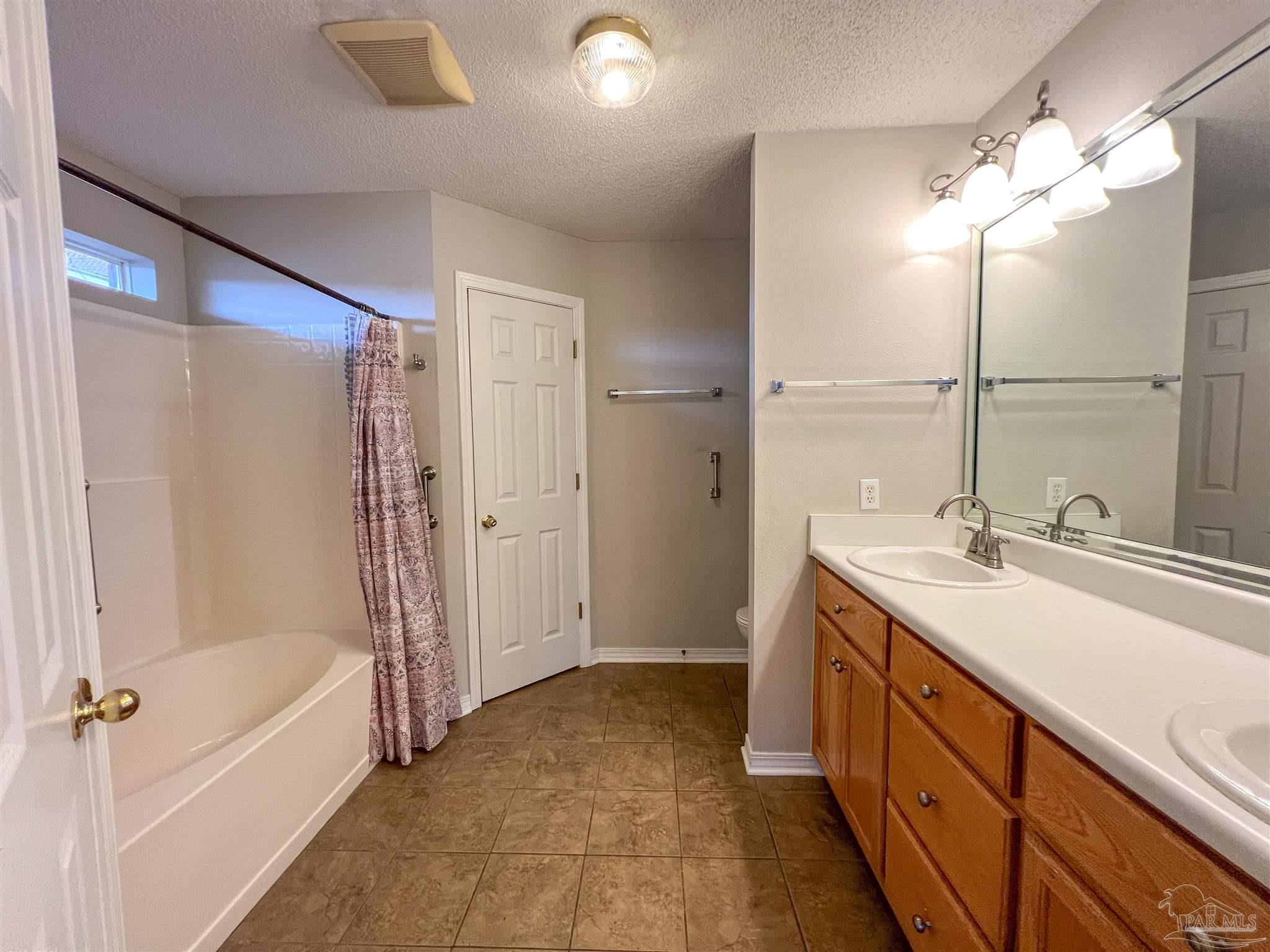 2967 Creole Way Pensacola, FL 32526 - Photo 15 of 30 a bathroom with a double vanity sink a mirror and a bathtub