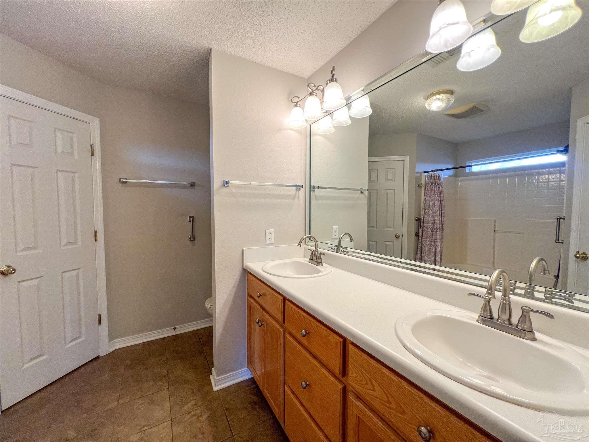 2967 Creole Way Pensacola, FL 32526 - Photo 16 of 30 a bathroom with a double vanity sink a mirror and a shower