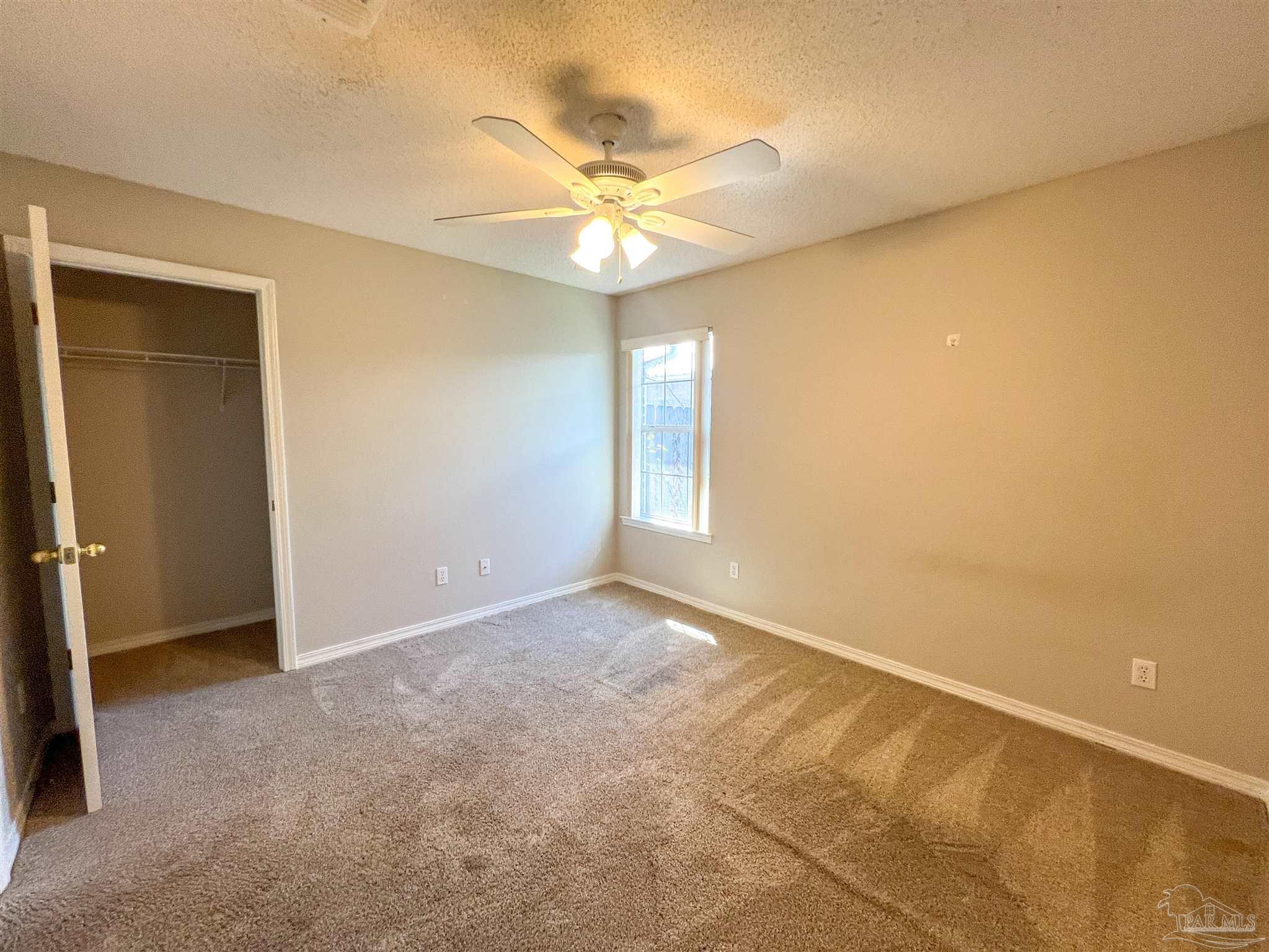 2967 Creole Way Pensacola, FL 32526 - Photo 27 of 30 an empty room with a chandelier fan and windows