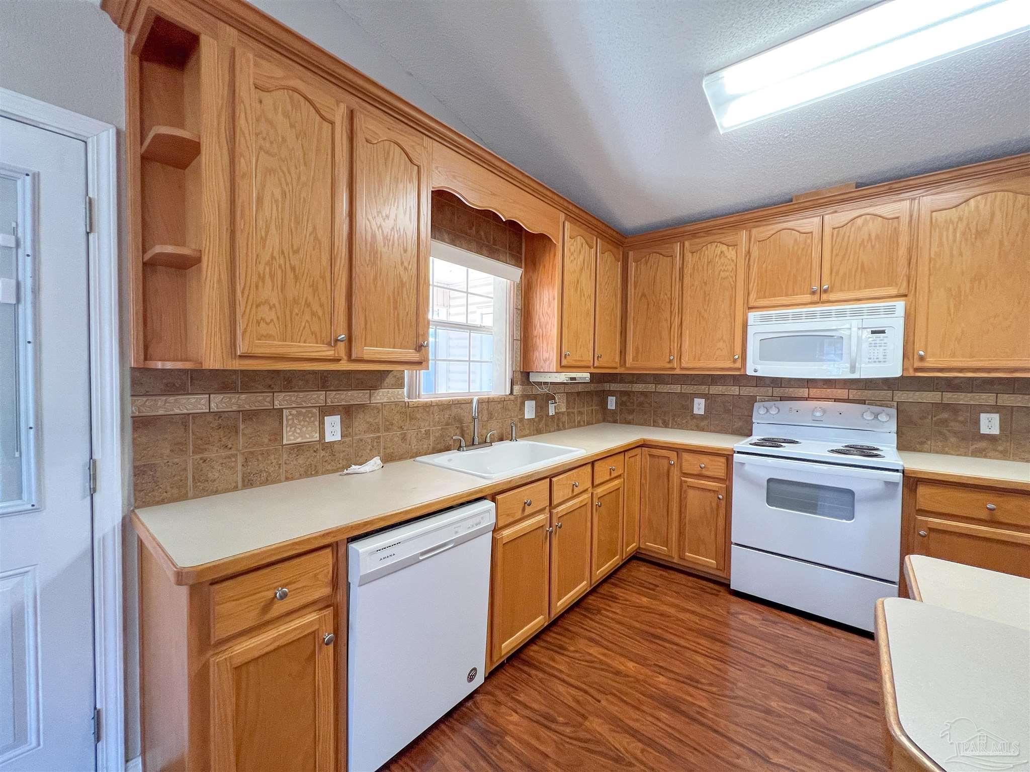 2967 Creole Way Pensacola, FL 32526 - Photo 9 of 30 a kitchen with a sink cabinets wooden floor and stainless steel appliances