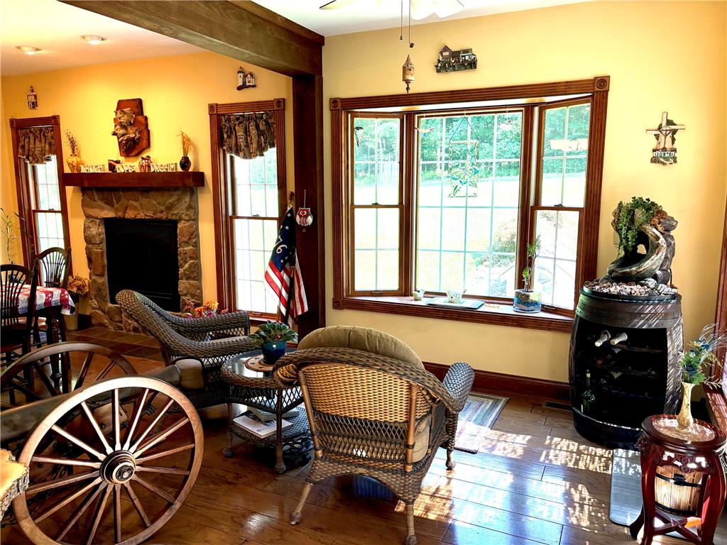 1222 Spring Road Andreas, PA 18211 - Photo 24 of 38 A warmly lit family room with hardwood floors, a stone fireplace, and a large bay window inviting natural light.