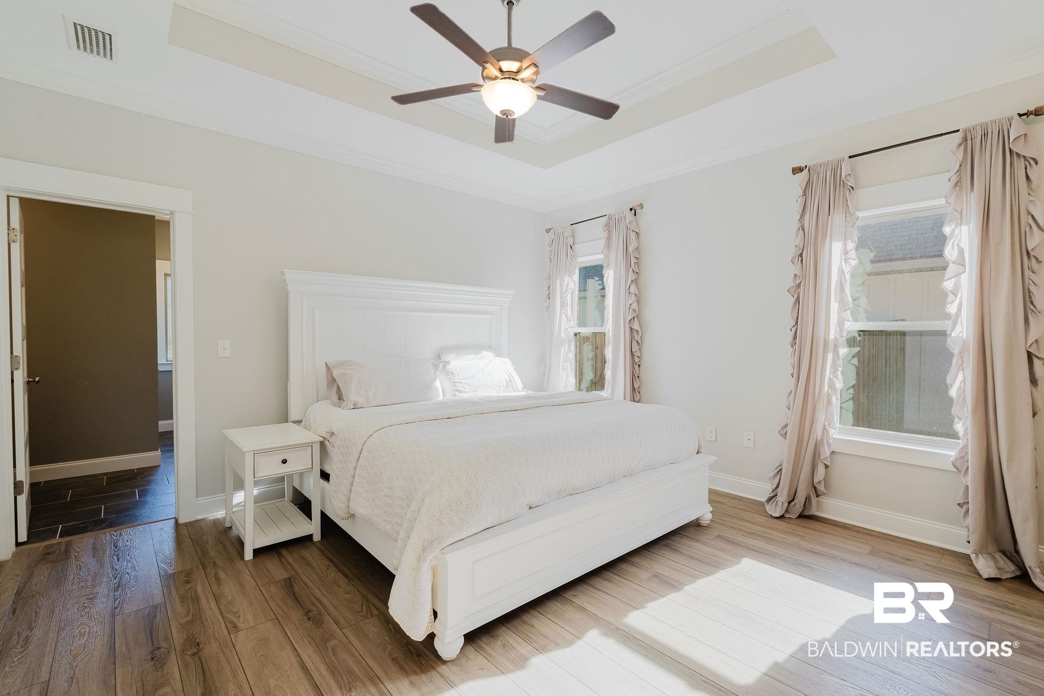 7872 Calverton Street Foley, AL 36535 - Photo 13 of 76 Spacious room featuring wood-finish flooring, a tray ceiling with a ceiling fan, and two windows with white trim