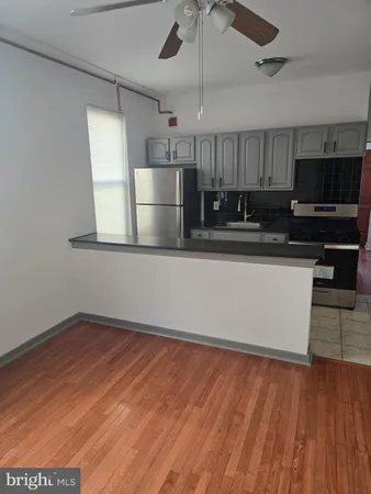 a kitchen with stainless steel appliances wooden floor and a refrigerator