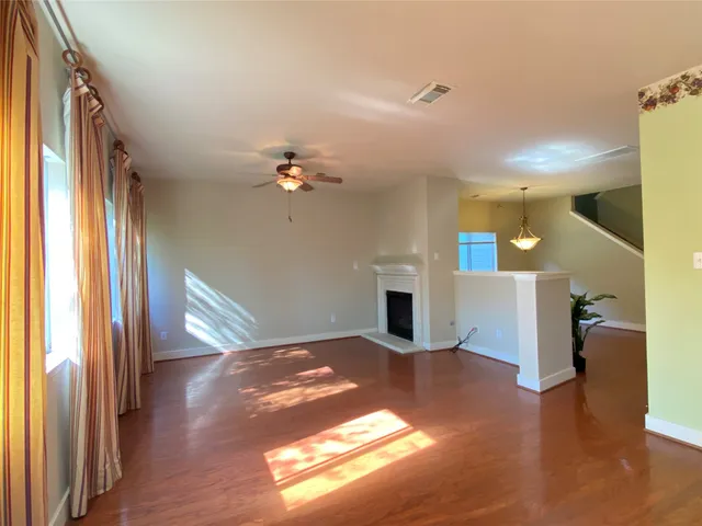 a view of an empty room with a window and wooden floor