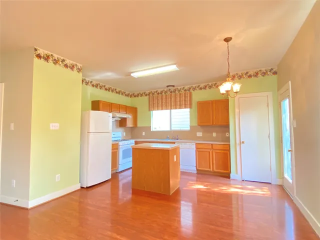 a open kitchen with stainless steel appliances granite countertop a refrigerator a sink dishwasher and a fireplace with wooden floor