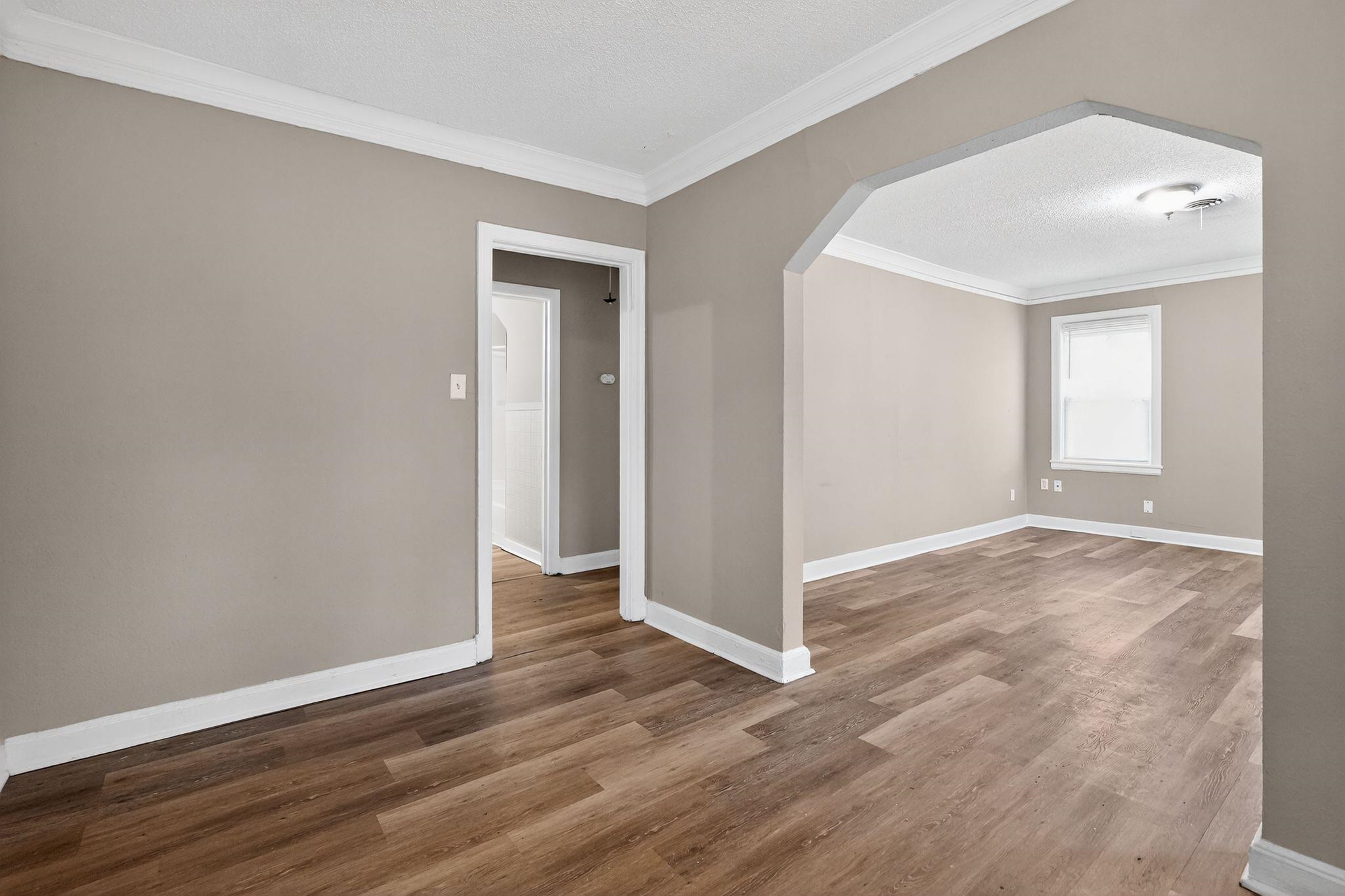 356 Hewlett Road Memphis, TN 38109 - Photo 9 of 30 Spare room featuring arched walkways, a textured ceiling, ornamental molding, and wood finished floors