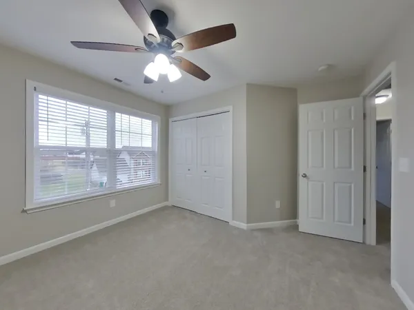 a view of an empty room with chandelier fan and fire place