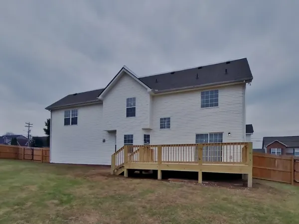 a view of backyard of house with wooden deck and furniture