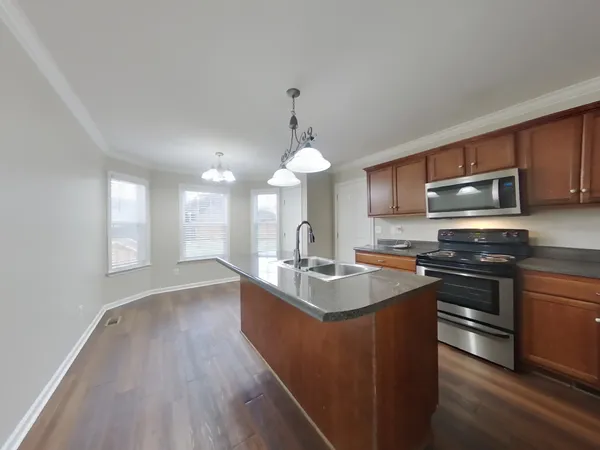 a kitchen with kitchen island granite countertop a sink stove and wooden floor