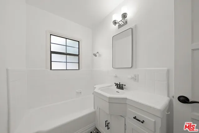 a bathroom with a bathtub sink vanity and mirror