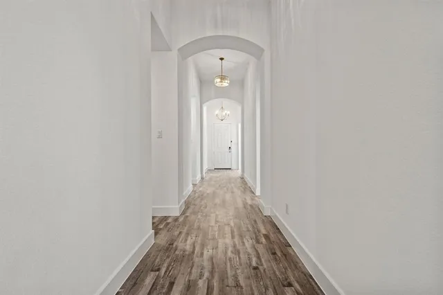 a large white kitchen with stainless steel appliances granite countertop a lot of counter space and wooden floors
