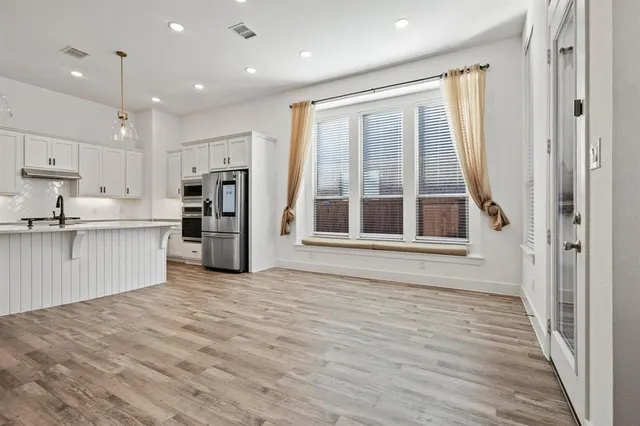 a view of an empty room with wooden floor fireplace and a window