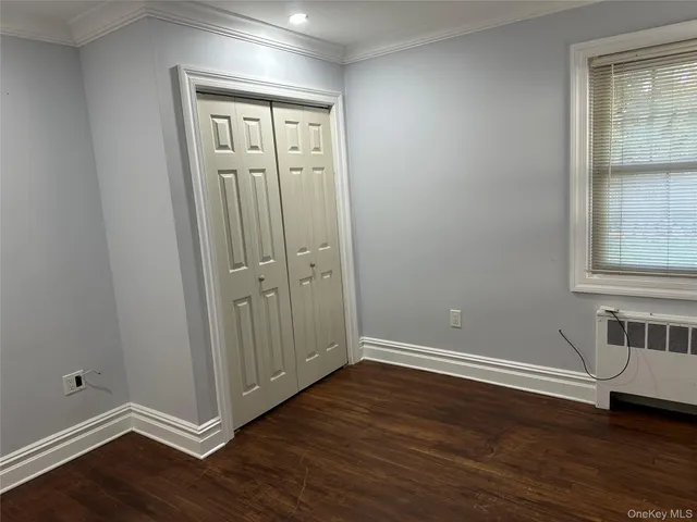 a view of empty room with wooden floor and closet