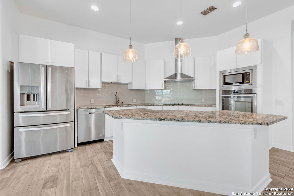1303 Summerfield San Antonio, TX 78258 - Photo 5 of 27 a kitchen with stainless steel appliances granite countertop a refrigerator a stove a sink and white cabinets