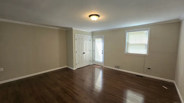 a view of an empty room with wooden floor and a window