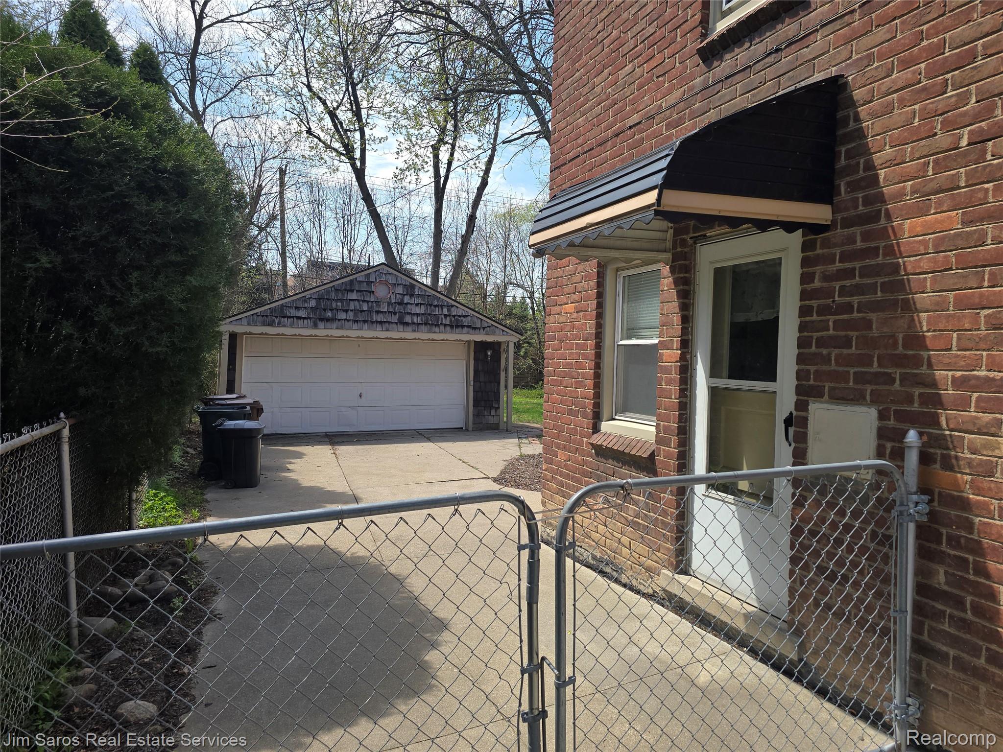 1705 Bournemouth Road Grosse Pointe, MI 48236 - Photo 14 of 20 View of property exterior featuring a gate, a garage, an outdoor structure, and brick siding