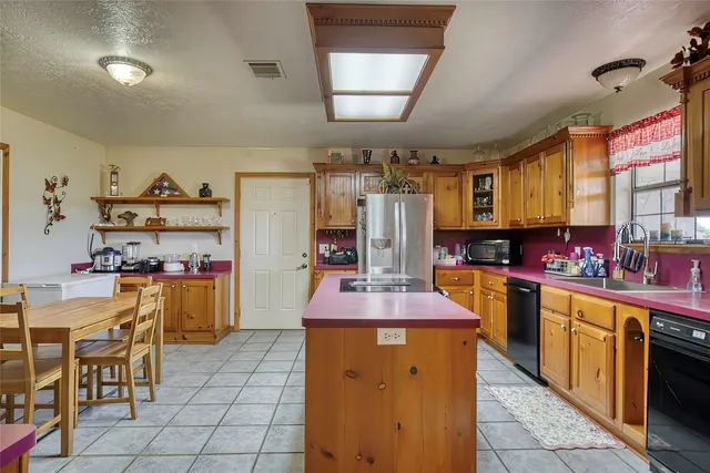 a kitchen with stainless steel appliances kitchen island granite countertop a table chairs in it and a window