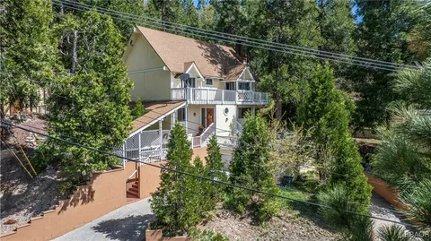 a view of a house with a small yard and large trees