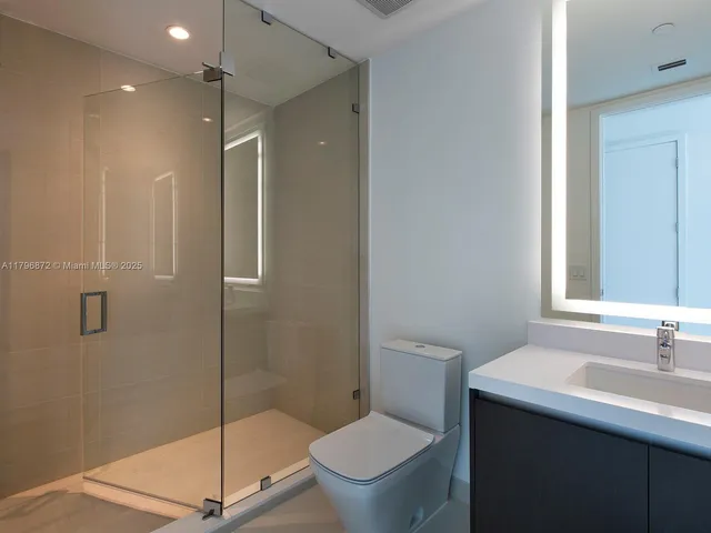 a bathroom with a shower sink vanity mirror and toilet
