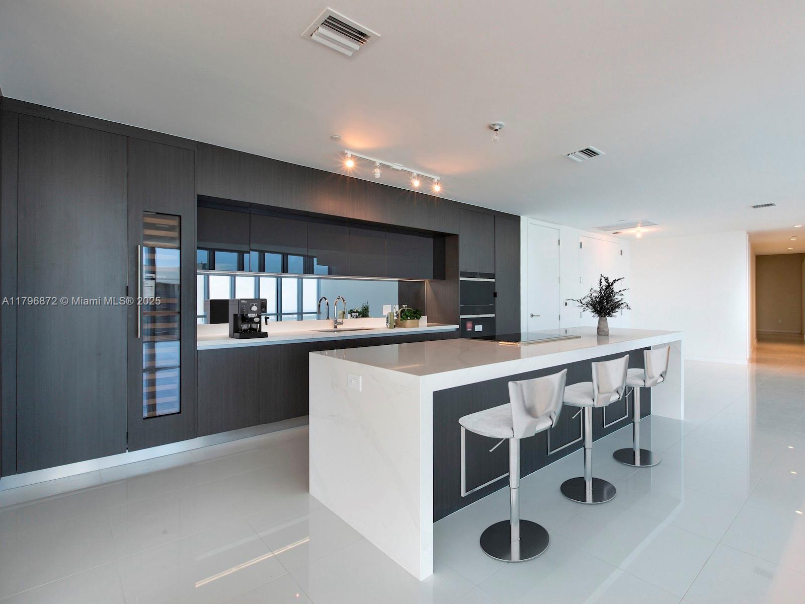851 Northeast 1st Avenue, Unit PH5011 Miami, FL 33132 - Photo 10 of 35 a kitchen with a table chairs sink and cabinets