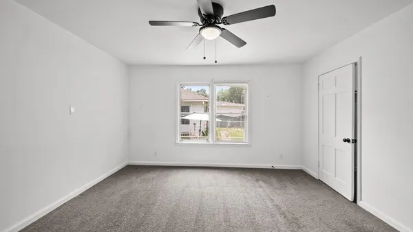 an empty room with a window and a fan