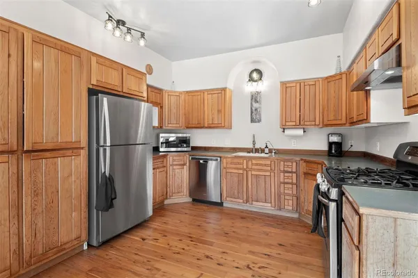 a kitchen with granite countertop a refrigerator stove top oven and sink
