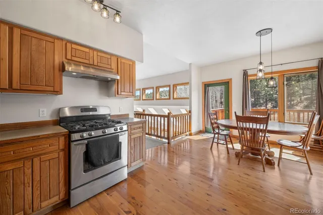 a kitchen with stainless steel appliances wooden floors and white cabinets
