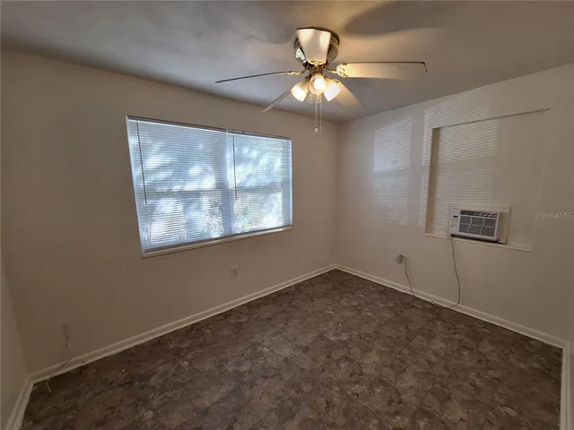 an empty room with a chandelier fan and windows