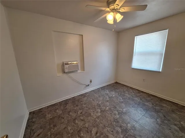 an empty room with a fan and a window