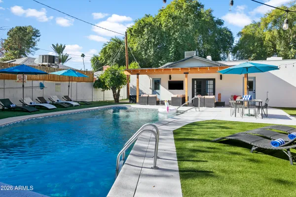 a view of a patio with couches and a table and chairs under an umbrella with large trees