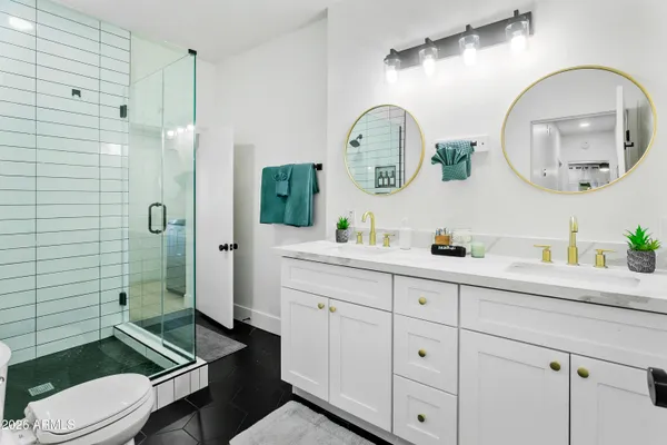 a spacious bathroom with a toilet a sink a mirror and shower