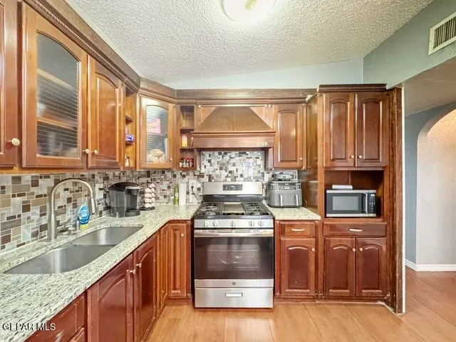 a kitchen with stainless steel appliances granite countertop a stove a sink and a microwave