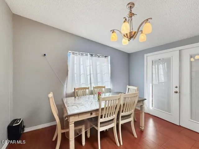 a dining room with wooden floor a chandelier a wooden table and chairs