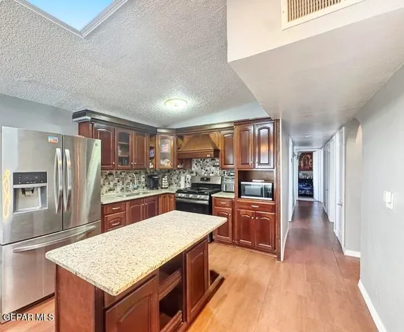 a kitchen with stainless steel appliances granite countertop a refrigerator oven stove sink and a large window