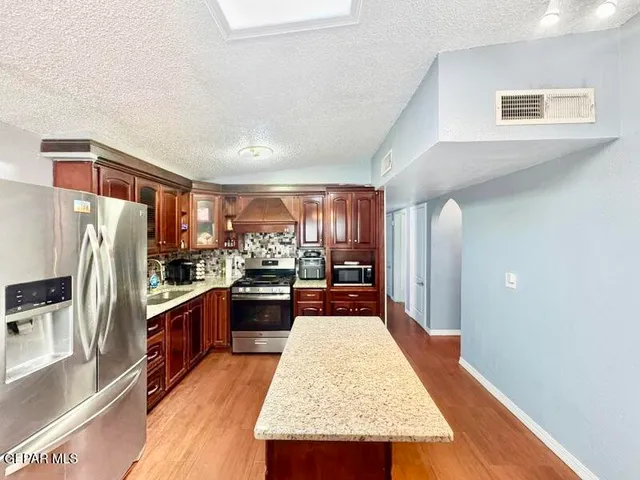 a kitchen with stainless steel appliances granite countertop a refrigerator a stove and a sink