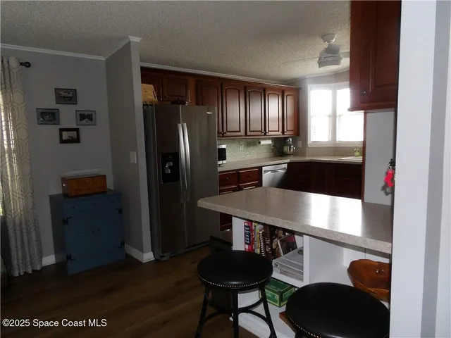 a kitchen with a refrigerator a stove a sink and a dining table with wooden floor