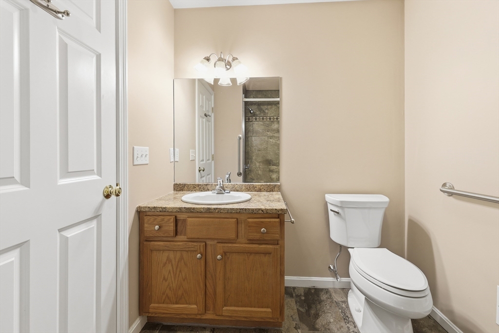 9 Rock Marsh Road, Unit B Wareham, MA 02571 - Photo 27 of 41 a bathroom with a granite countertop toilet a sink and a mirror