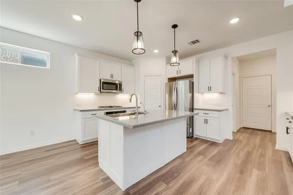 a kitchen with stainless steel appliances granite countertop a sink a stove a refrigerator and island with wooden floor